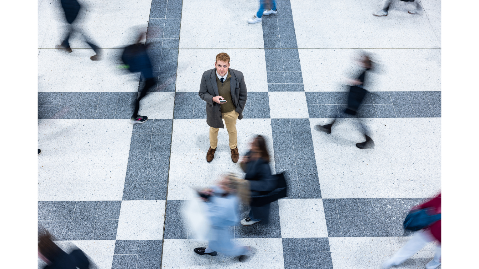 A person standing still while others rush past in a busy public space
